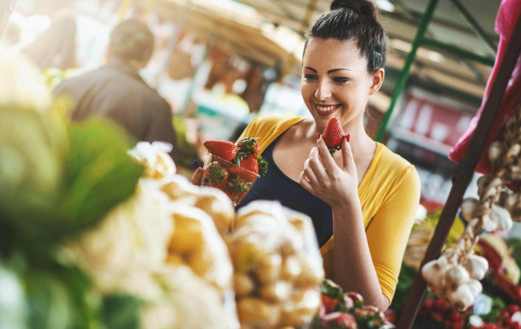 A woman sampling vegetables at a farm stall